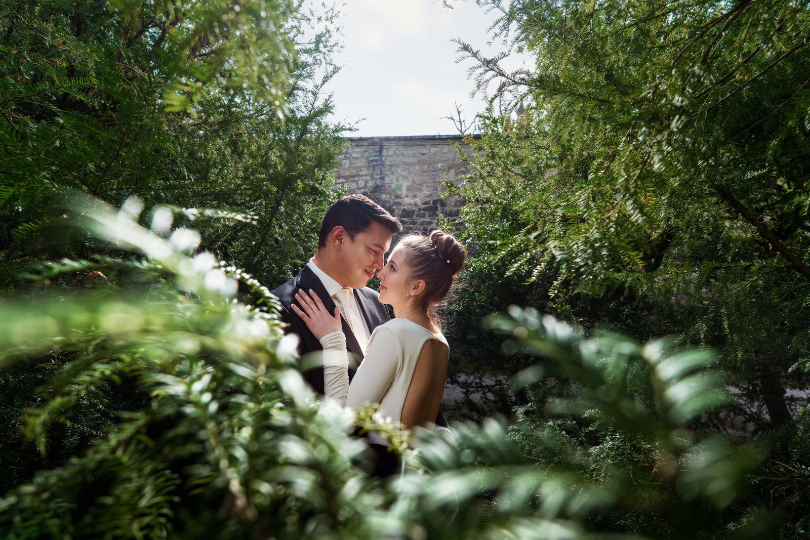 hochzeitsfoto vom hochzeitspaar, das im grünen Schlosspark einander tief in die Augen guckt